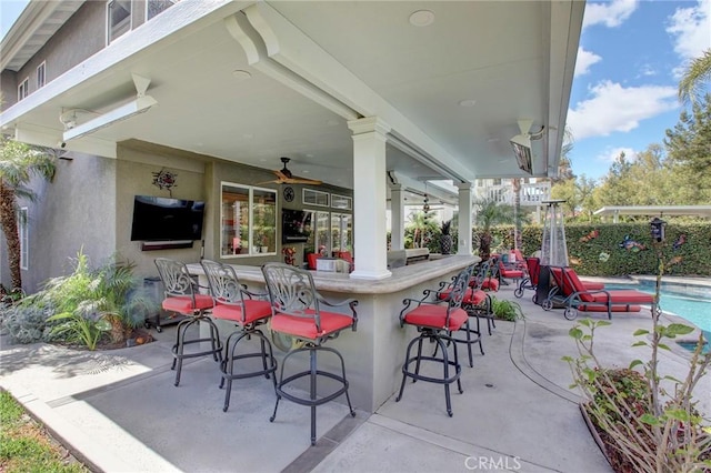 view of patio / terrace with a fenced in pool, a bar, and a ceiling fan