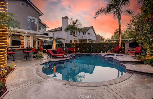 view of swimming pool featuring a patio, a pool with connected hot tub, and outdoor dry bar