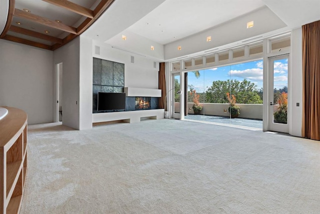 unfurnished living room featuring a high ceiling, carpet flooring, visible vents, and a warm lit fireplace