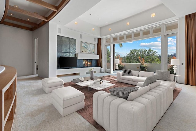 carpeted living area featuring visible vents, a glass covered fireplace, and a towering ceiling