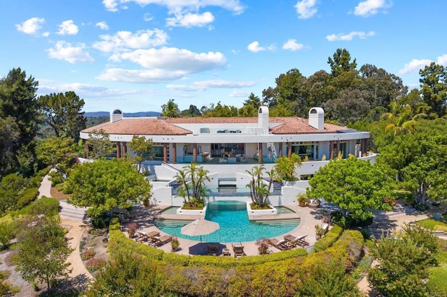 back of house featuring a jacuzzi, a patio area, an outdoor pool, and a chimney