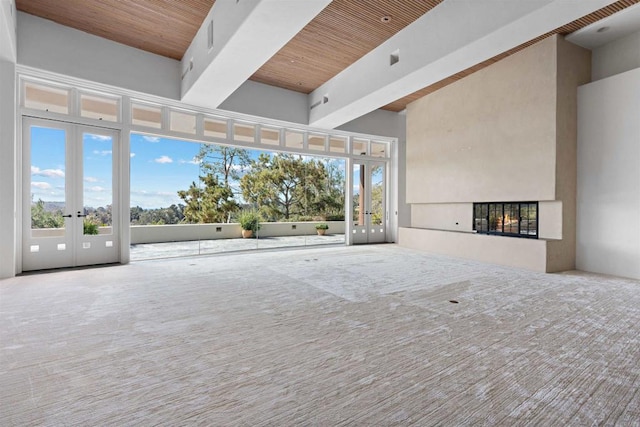 unfurnished living room featuring carpet flooring, wooden ceiling, french doors, a fireplace, and a high ceiling