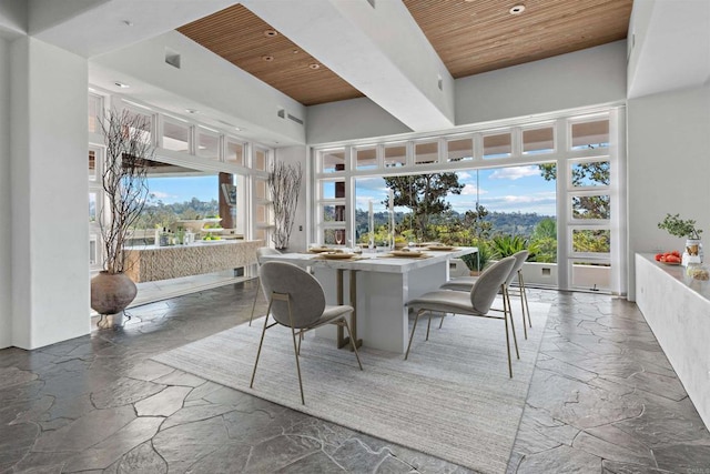 dining area featuring a high ceiling, wood ceiling, and stone tile flooring