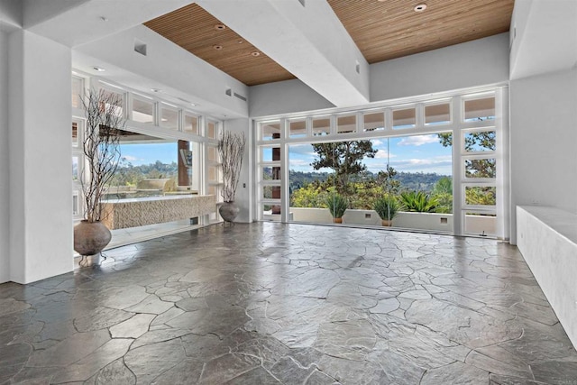 interior space featuring wooden ceiling, a high ceiling, plenty of natural light, and stone tile flooring