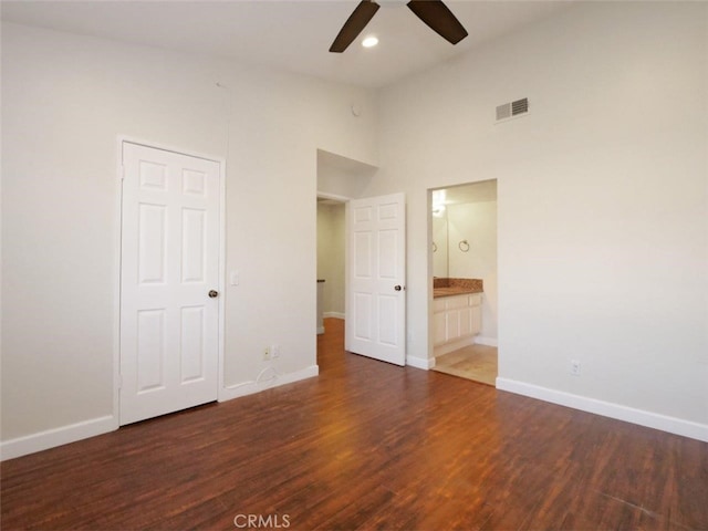 unfurnished bedroom with visible vents, ensuite bath, baseboards, and wood finished floors