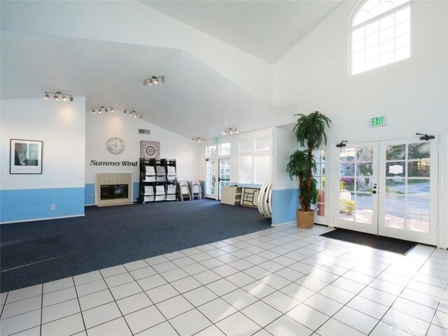 interior space with a glass covered fireplace, tile patterned floors, carpet, and french doors