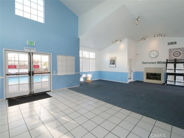 interior space with tile patterned floors, visible vents, high vaulted ceiling, carpet floors, and a fireplace