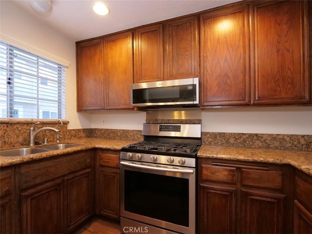 kitchen featuring brown cabinets, stainless steel appliances, and a sink