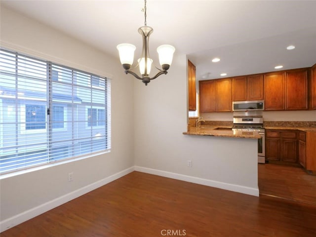 kitchen featuring brown cabinetry, dark wood-style flooring, appliances with stainless steel finishes, and baseboards