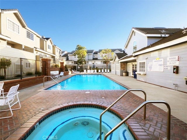 community pool with a patio, fence, a residential view, and a hot tub