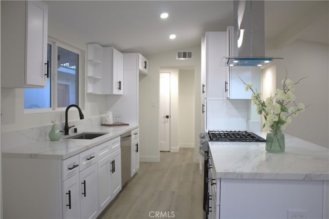 kitchen featuring visible vents, stainless steel appliances, island range hood, white cabinetry, and a sink