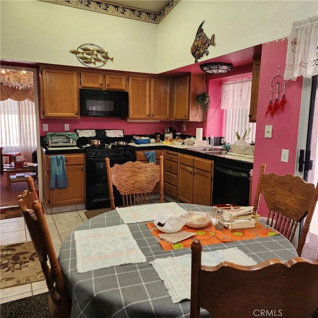 kitchen featuring light tile patterned flooring, brown cabinets, black appliances, and tile counters