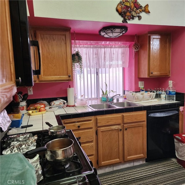 kitchen with tile patterned flooring, black appliances, tile counters, and a sink