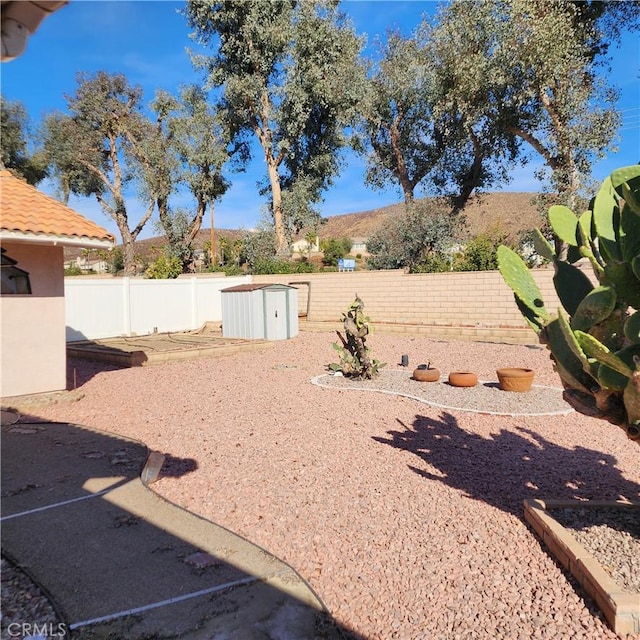 view of yard featuring an outbuilding, a fenced backyard, and a storage shed