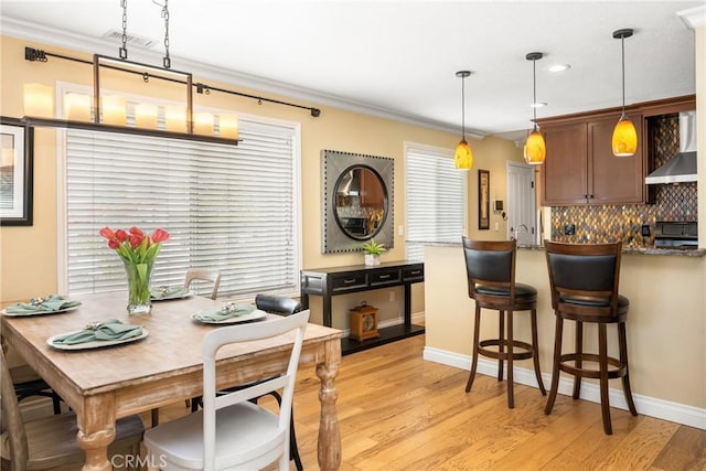 dining area with a healthy amount of sunlight, crown molding, and light wood finished floors