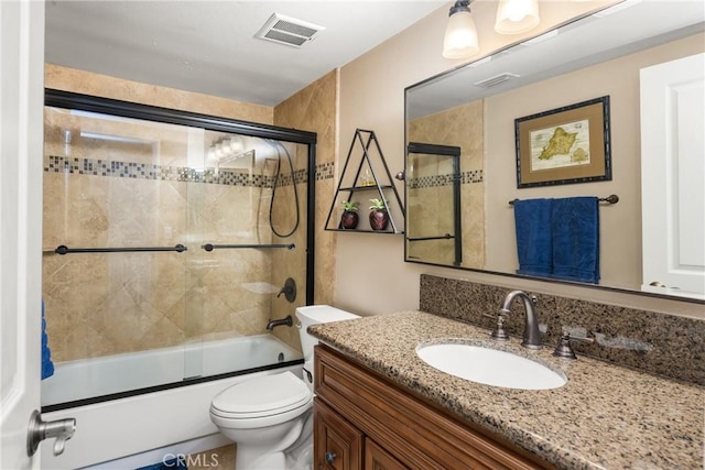 bathroom featuring visible vents, enclosed tub / shower combo, toilet, and vanity