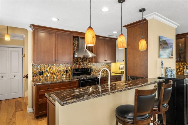 kitchen featuring wall chimney exhaust hood, tasteful backsplash, and black range with gas stovetop