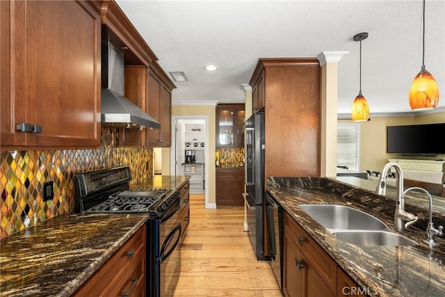 kitchen featuring light wood-type flooring, black appliances, ornamental molding, a sink, and wall chimney range hood