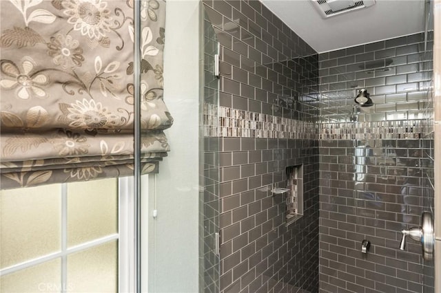 full bathroom with a tile shower and visible vents