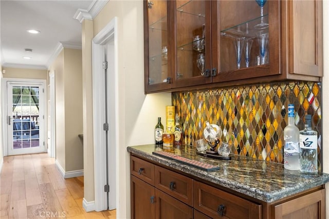 bar featuring a dry bar, light wood-type flooring, tasteful backsplash, and ornamental molding