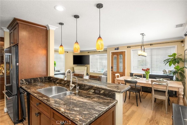 kitchen featuring visible vents, light wood-style flooring, brown cabinets, black appliances, and a sink