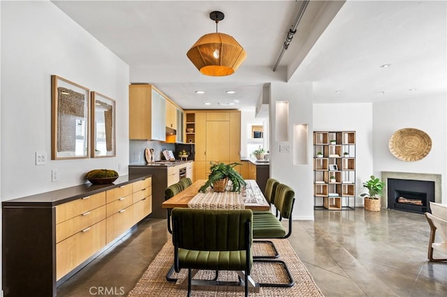 dining area with recessed lighting, rail lighting, finished concrete floors, and a fireplace