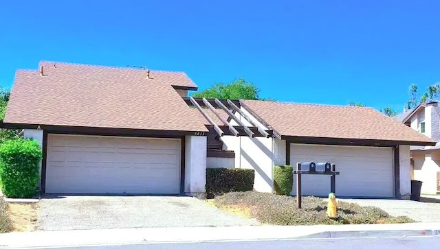 view of front of house with stucco siding, a garage, and roof with shingles