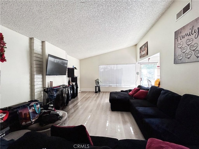 living room featuring vaulted ceiling, wood finished floors, visible vents, and a textured ceiling