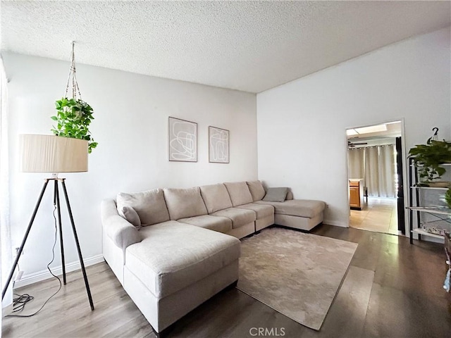 living area featuring wood finished floors, baseboards, and a textured ceiling