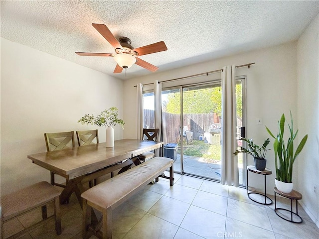 dining space featuring light tile patterned floors, a ceiling fan, and a textured ceiling