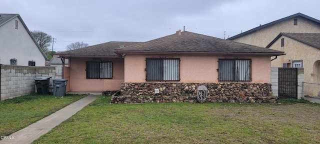 exterior space featuring stucco siding, fence, a lawn, and a shingled roof