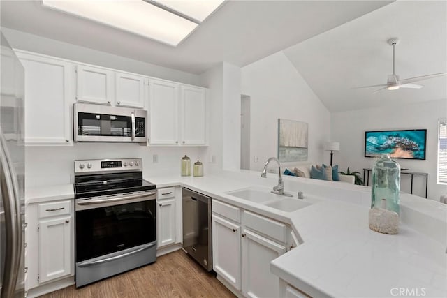 kitchen with light wood-style flooring, a sink, white cabinetry, appliances with stainless steel finishes, and light countertops