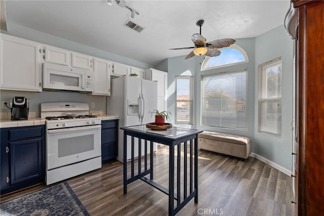 kitchen featuring visible vents, blue cabinetry, dark wood finished floors, white appliances, and ceiling fan