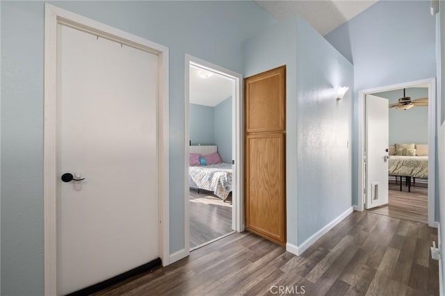 hallway featuring baseboards and dark wood-type flooring