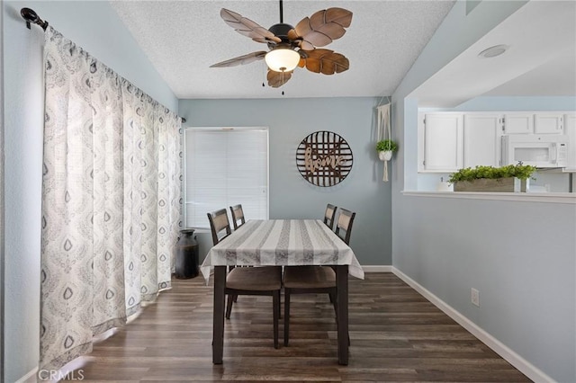 dining area featuring dark wood finished floors, a ceiling fan, baseboards, and a textured ceiling