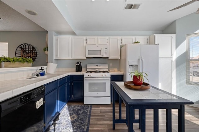 kitchen with blue cabinetry, visible vents, white appliances, and white cabinets