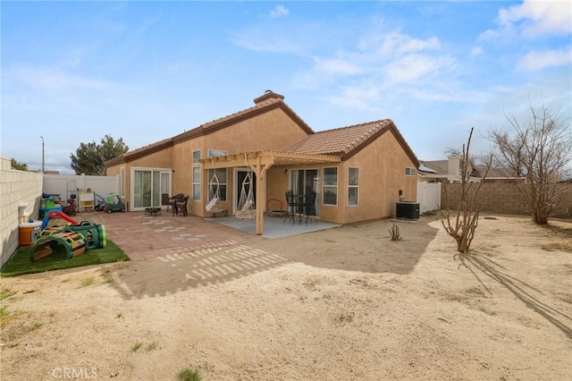 back of property with a fenced backyard, stucco siding, a tiled roof, and a patio