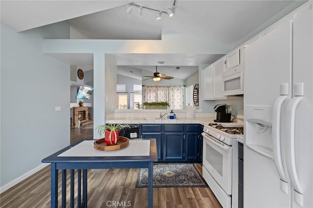 kitchen with white appliances, wood finished floors, blue cabinetry, a sink, and vaulted ceiling