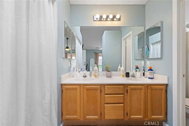 full bathroom with double vanity, toilet, and a sink