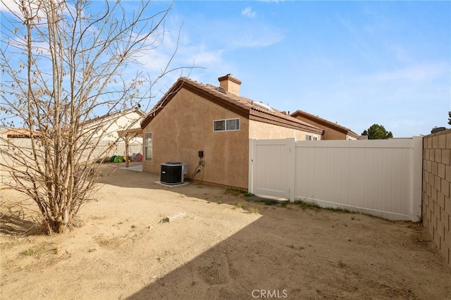 view of home's exterior featuring fence, stucco siding, cooling unit, a chimney, and a patio area