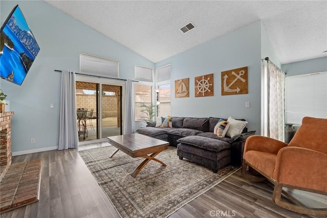 living area with visible vents, baseboards, a fireplace, wood finished floors, and a textured ceiling