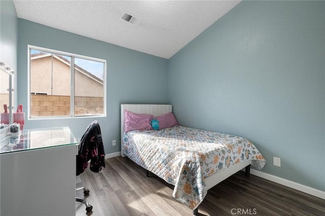 bedroom featuring visible vents, a textured ceiling, wood finished floors, baseboards, and vaulted ceiling