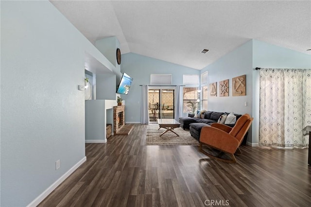 living area featuring visible vents, baseboards, lofted ceiling, and wood finished floors