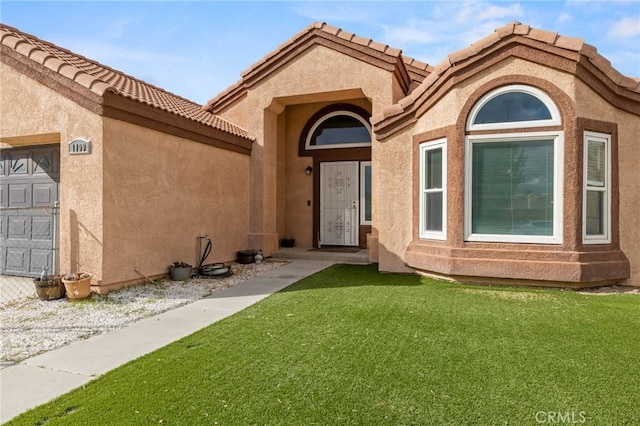 view of front of home featuring a garage, a tile roof, a front yard, and stucco siding