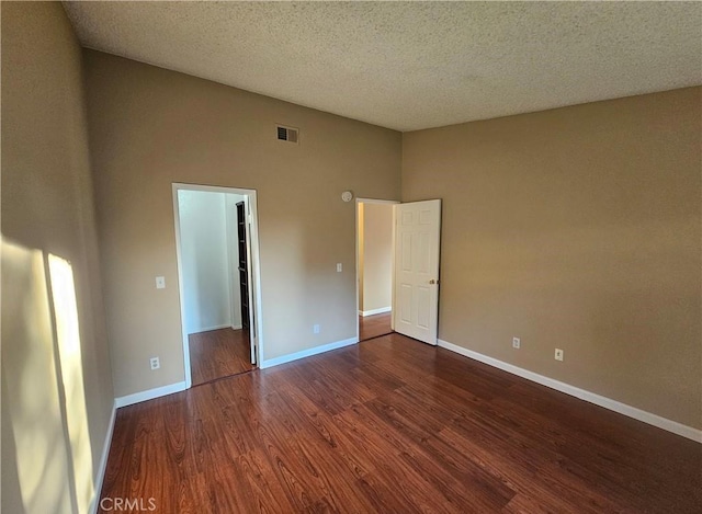 unfurnished room featuring visible vents, a textured ceiling, baseboards, and wood finished floors