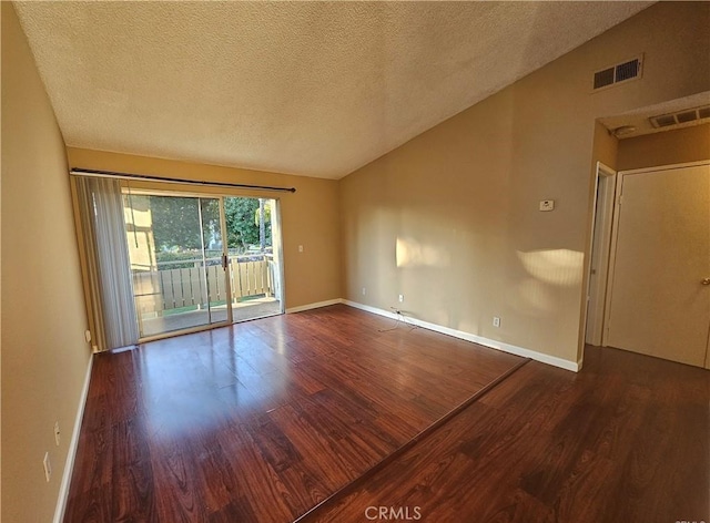 empty room with visible vents, baseboards, wood finished floors, and vaulted ceiling