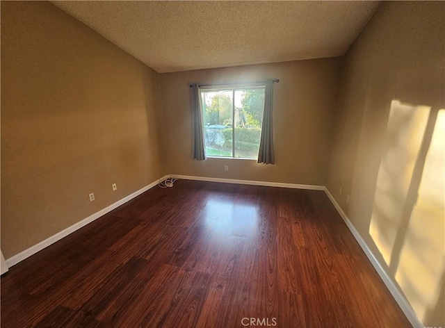 unfurnished room with baseboards, a textured ceiling, and dark wood-style floors