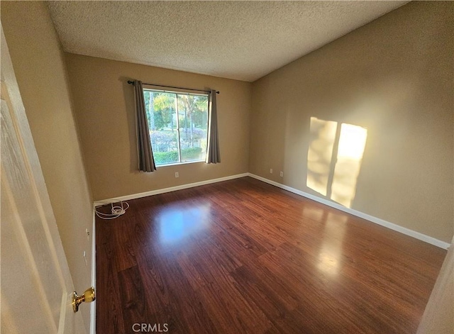 empty room with a textured ceiling, baseboards, and dark wood-style flooring