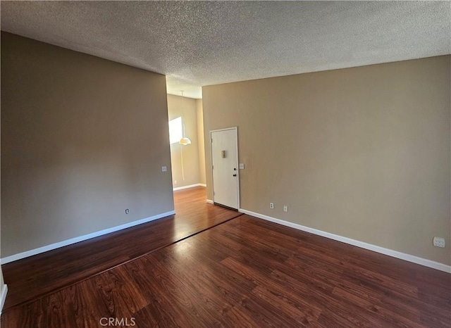 unfurnished room with a textured ceiling, baseboards, and wood finished floors