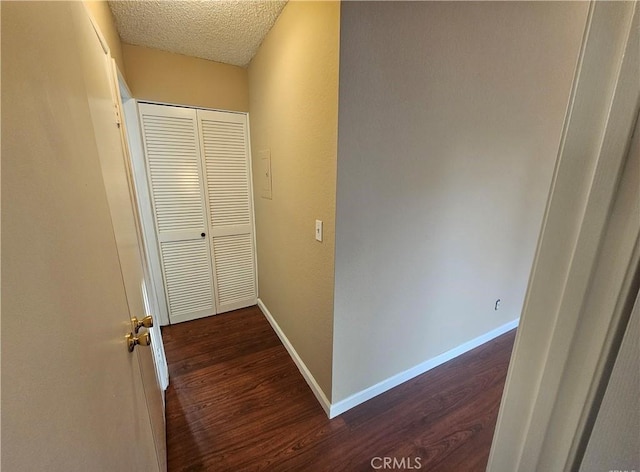 hall with baseboards, a textured ceiling, and dark wood-style floors